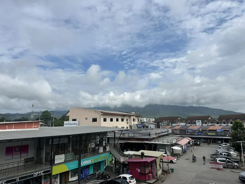 View from the studio balcony over Mae Hia market to the forested mountains under a big cloudy sky